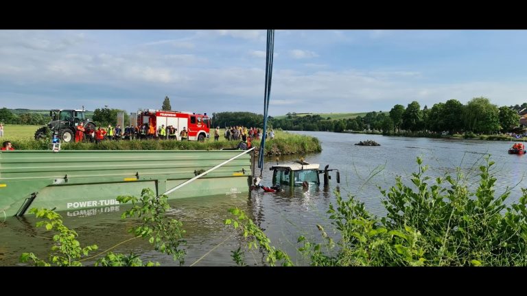 Trekker met aanhanger geladen met gras rijdt achteruit de Main in